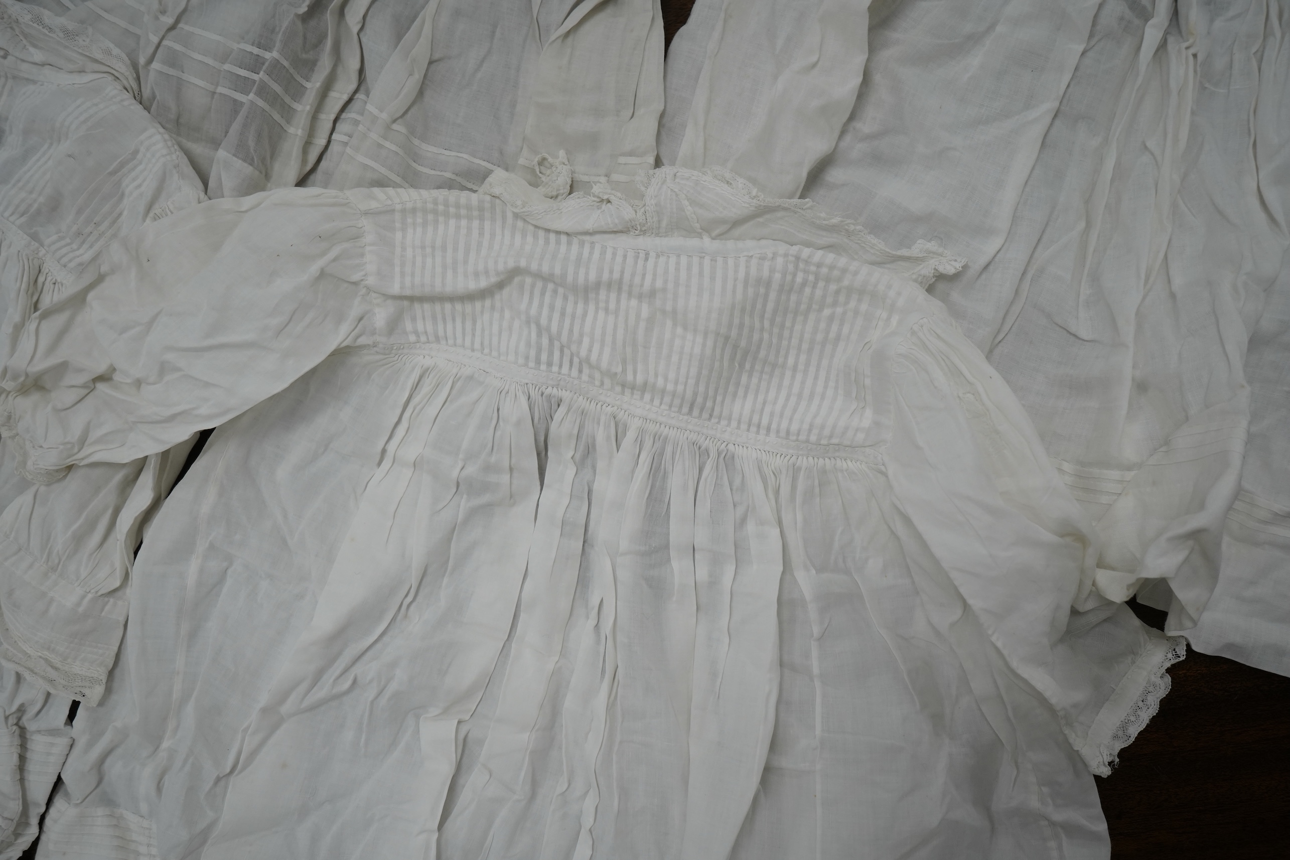 An early 20th century cream silk young girls day dress, together with six similar sized cotton and fine lawn day dresses and a bonnet, all dresses worked with tucking, feather stitching, some lace edged, the bonnet made